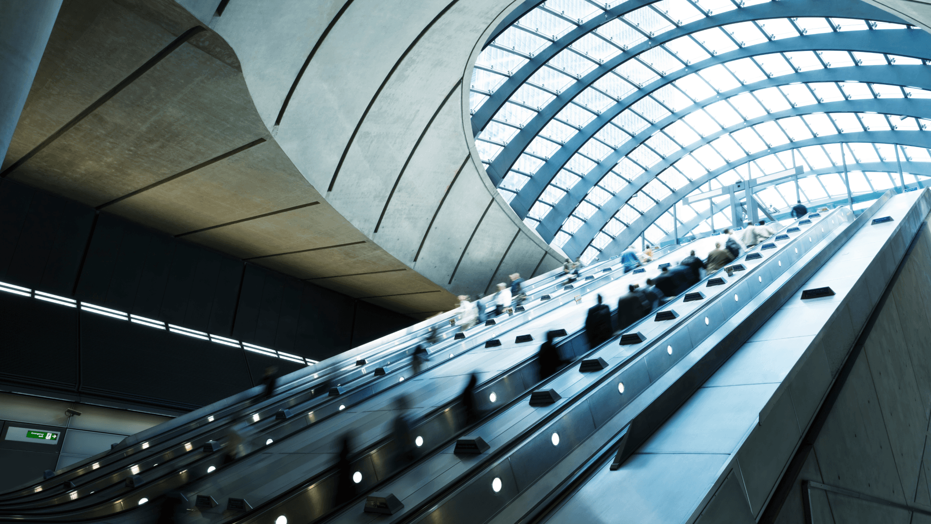 Commuters on escalators at Canary Wharf Subway Station, financial district, UK