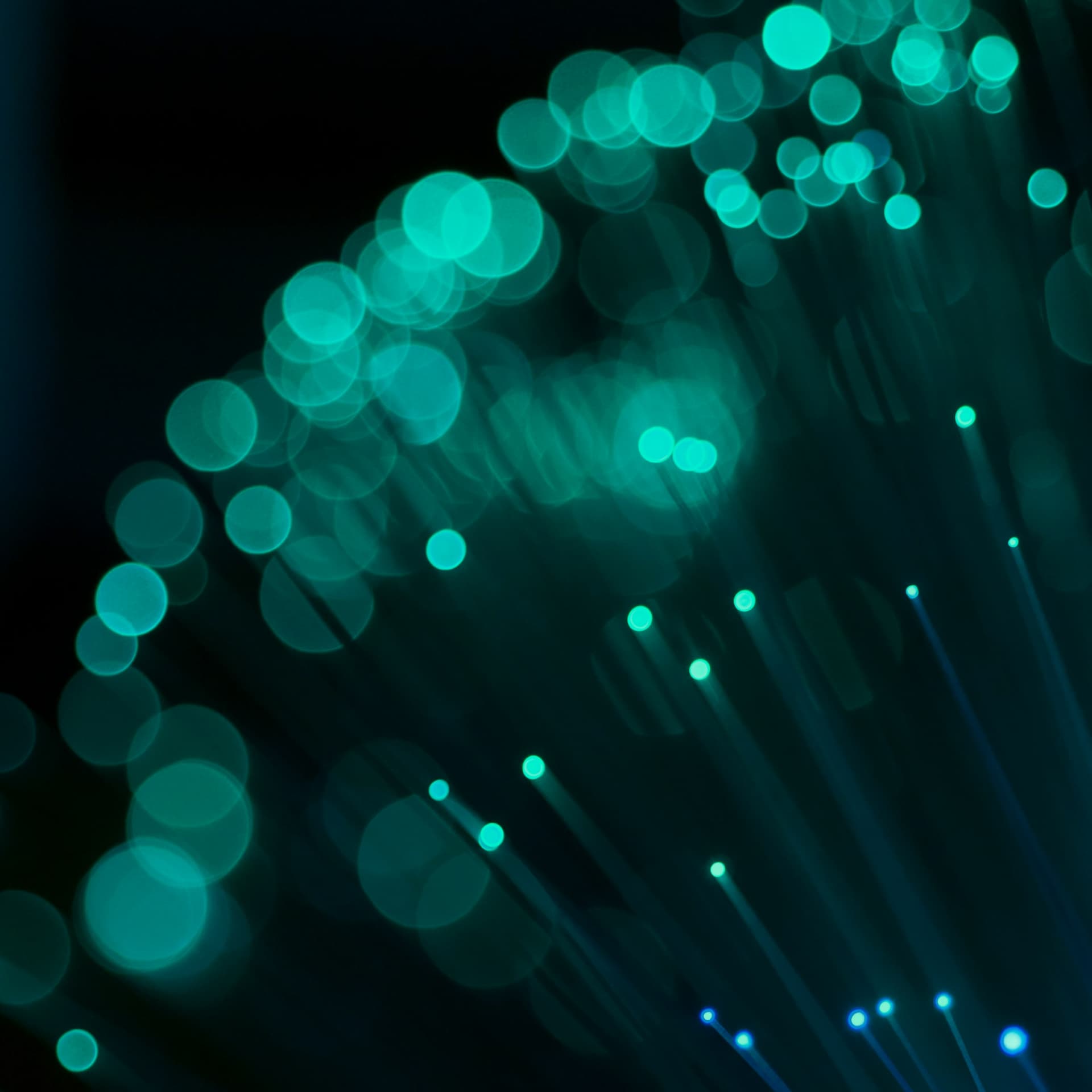 A series of blurred turquoise dots are set against a black background.