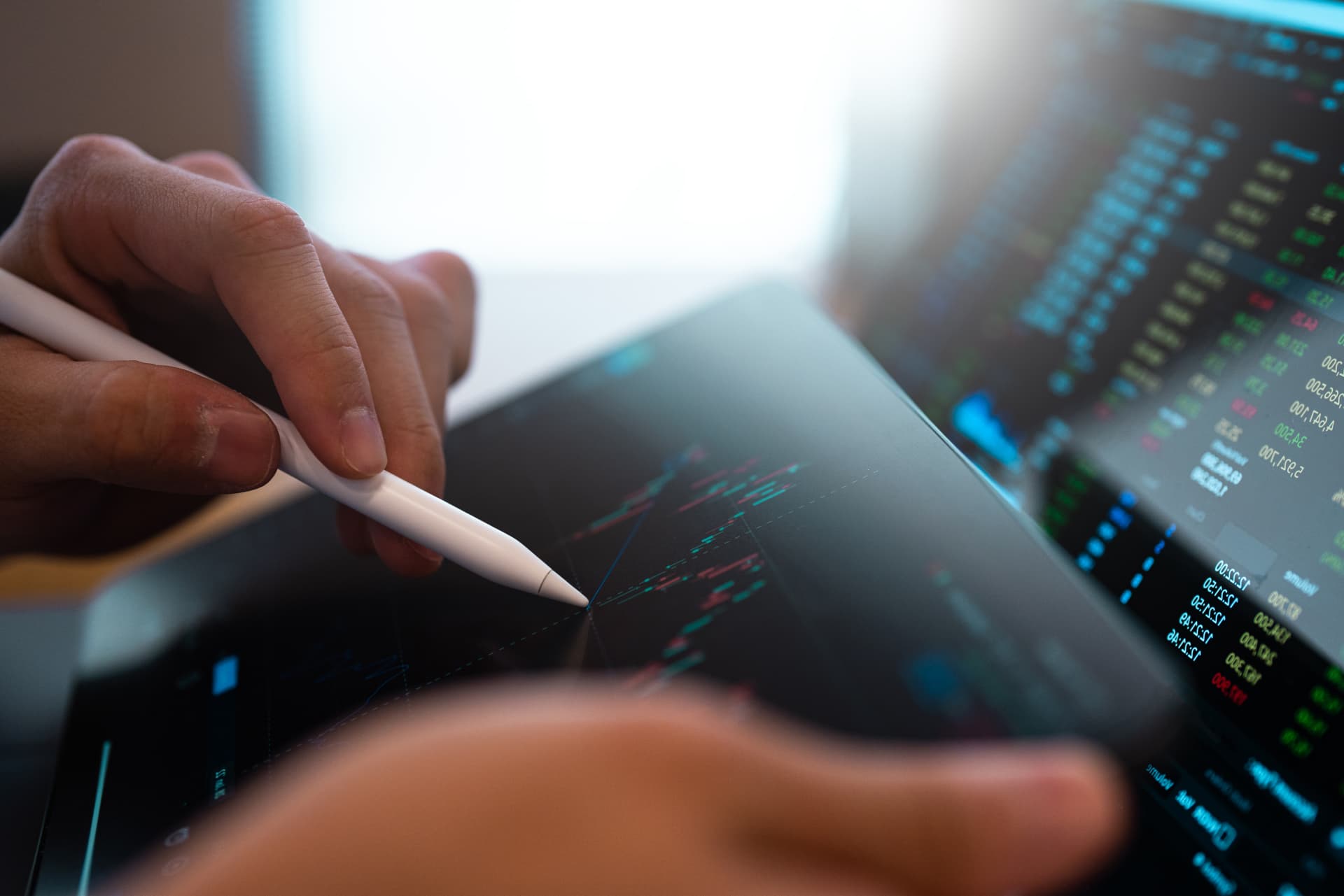 A business person tracking the technical movement of a stock chart on a computer screen.