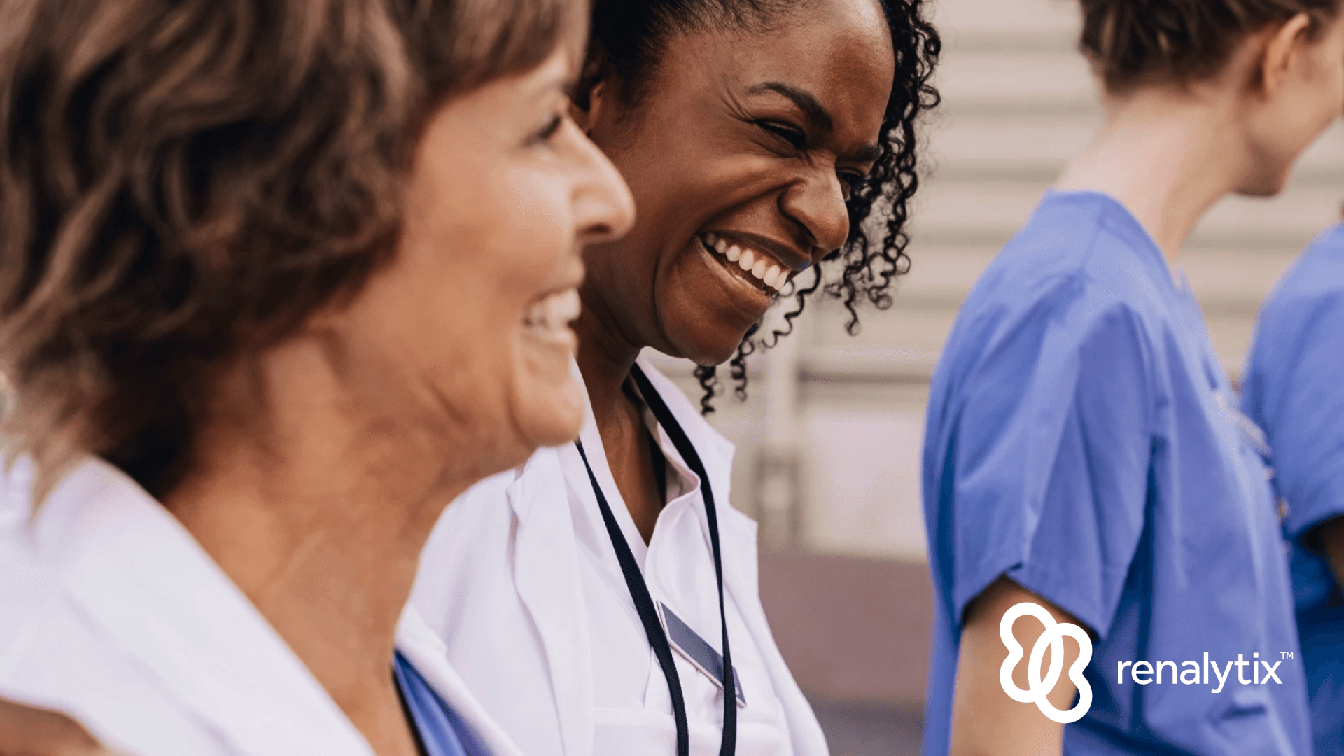 Happy female physician with arm around colleague outside hospital