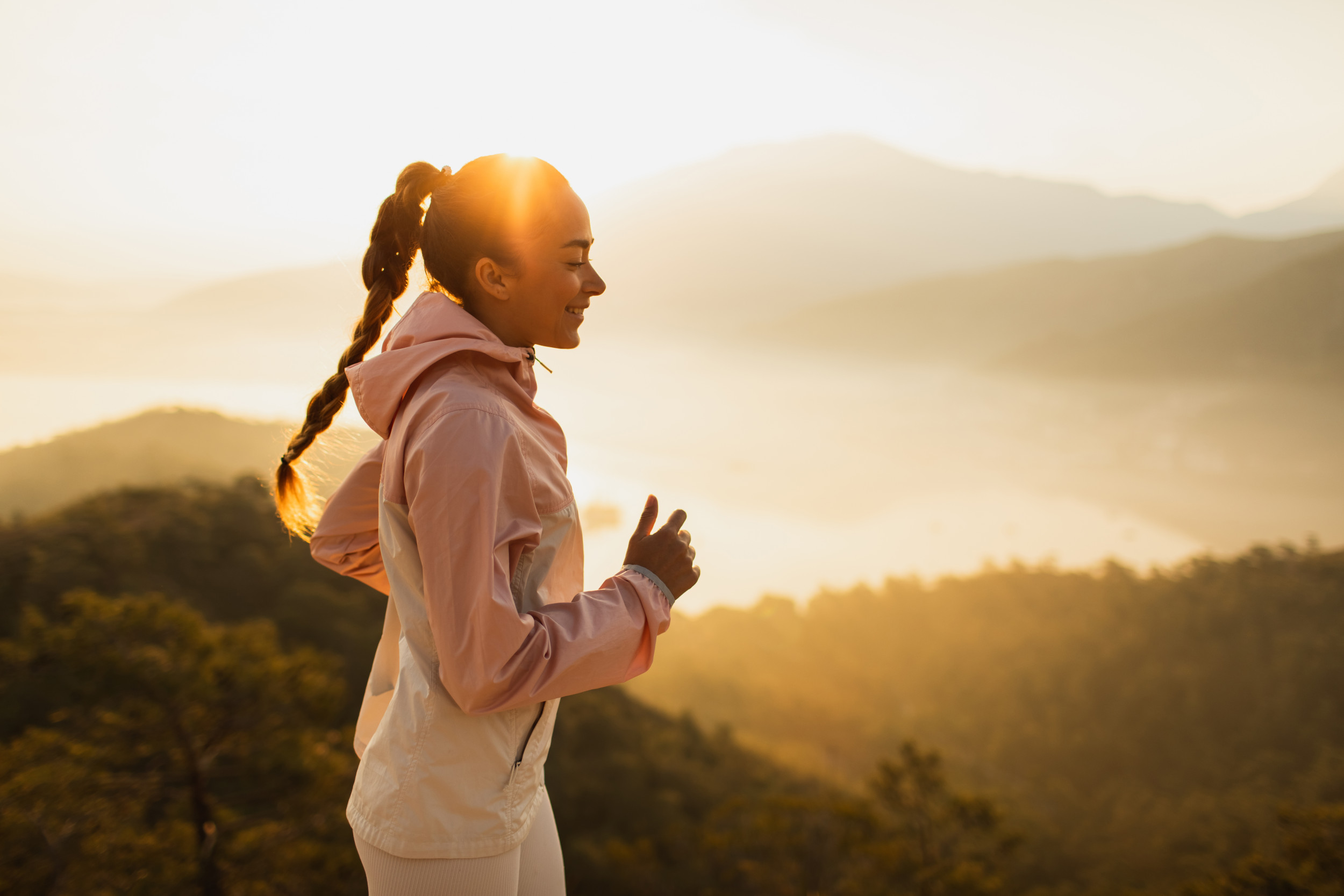 Puma - Happy young woman running outdoors with mountain view at sunset